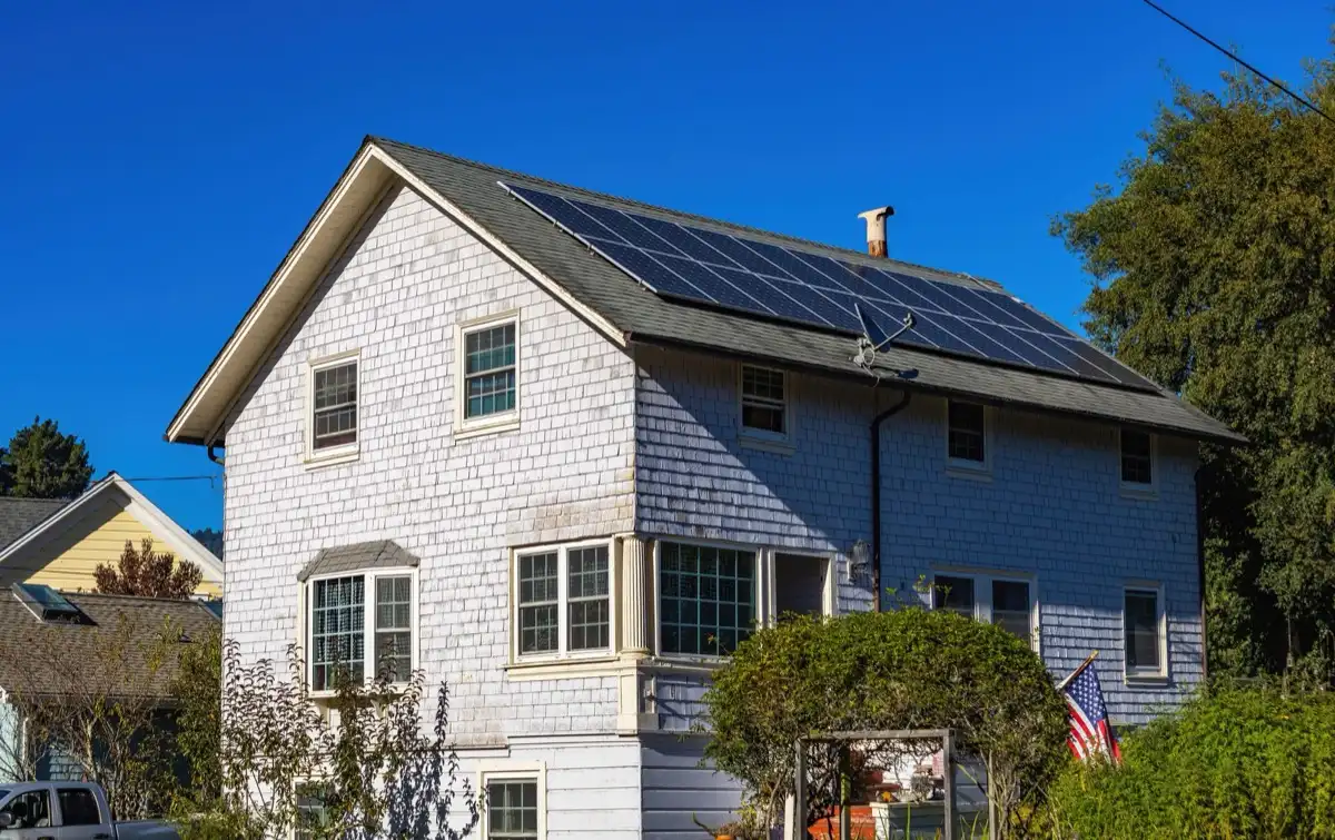 Rooftop solar array mounted on the asphalt shingle roof of a two-story shingle-sided house